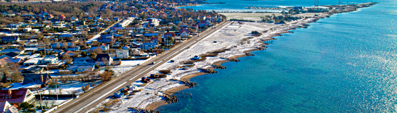 A beautiful view of the Kalundborg coastline in Denmark, featuring calm waters, rocky shores, and a serene blue sky.