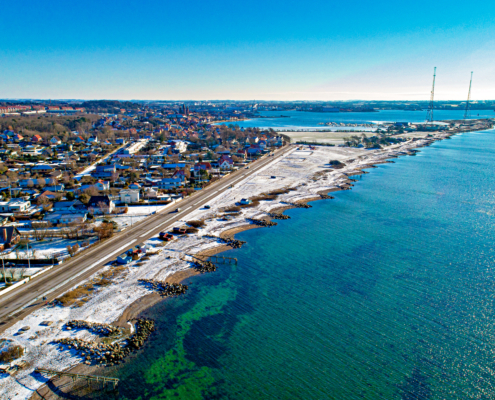 A beautiful view of the Kalundborg coastline in Denmark, featuring calm waters, rocky shores, and a serene blue sky.